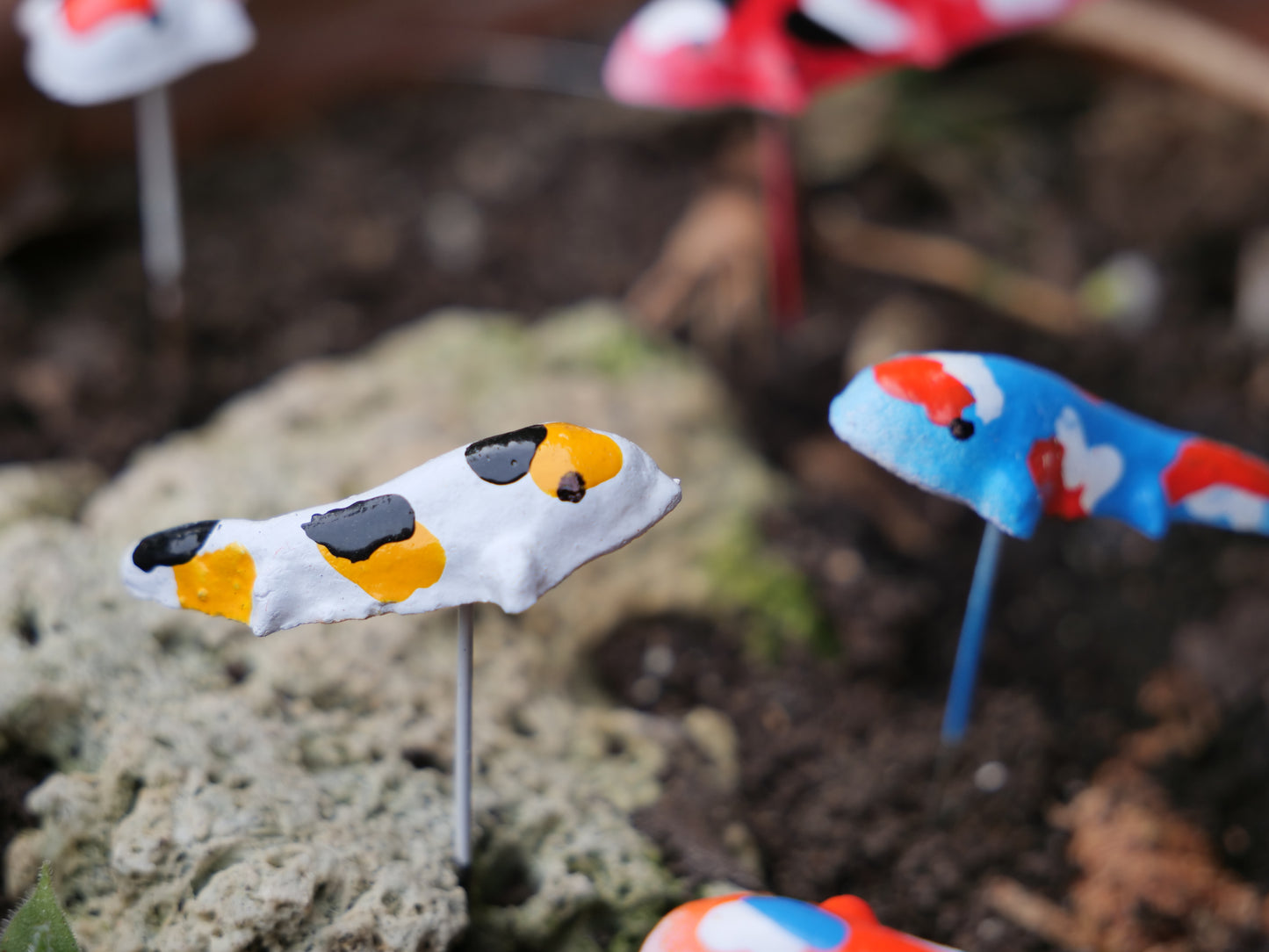 Nahaufnahme eines Koi-Fischs aus Terrakotta, handbemalt in Weiß, Orange und Schwarz, auf Stift für Gartendekoration,Miniteiche und Balkon