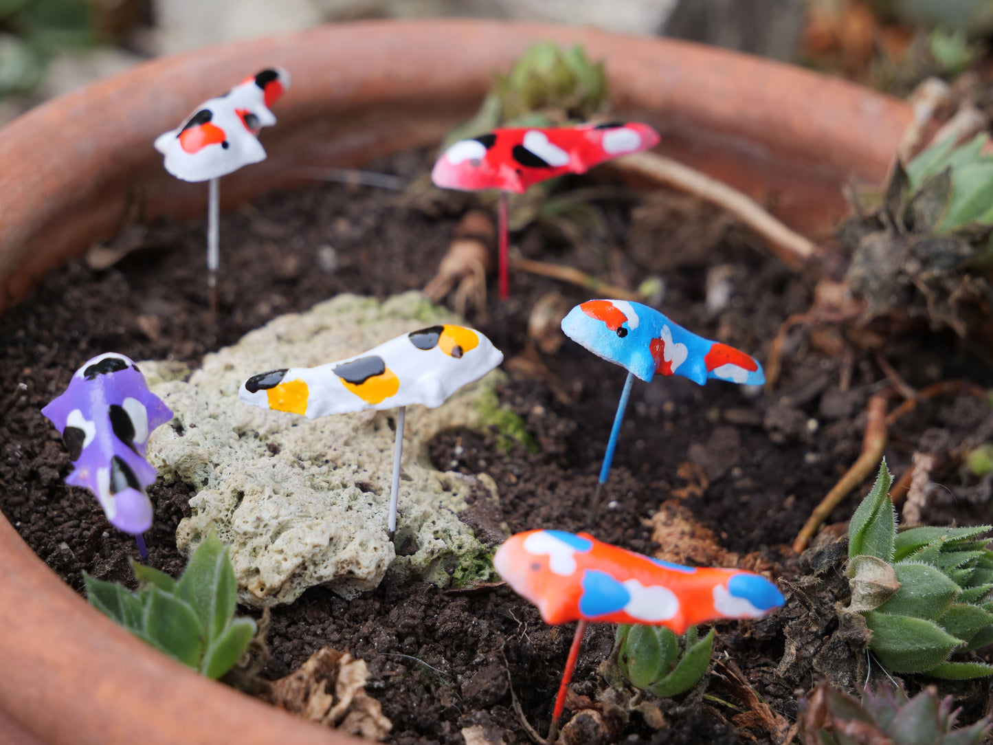 Mehrere handbemalte Koi-Figuren aus Terrakotta auf Stiften, bunte Deko für Miniteiche, Balkon und Garten