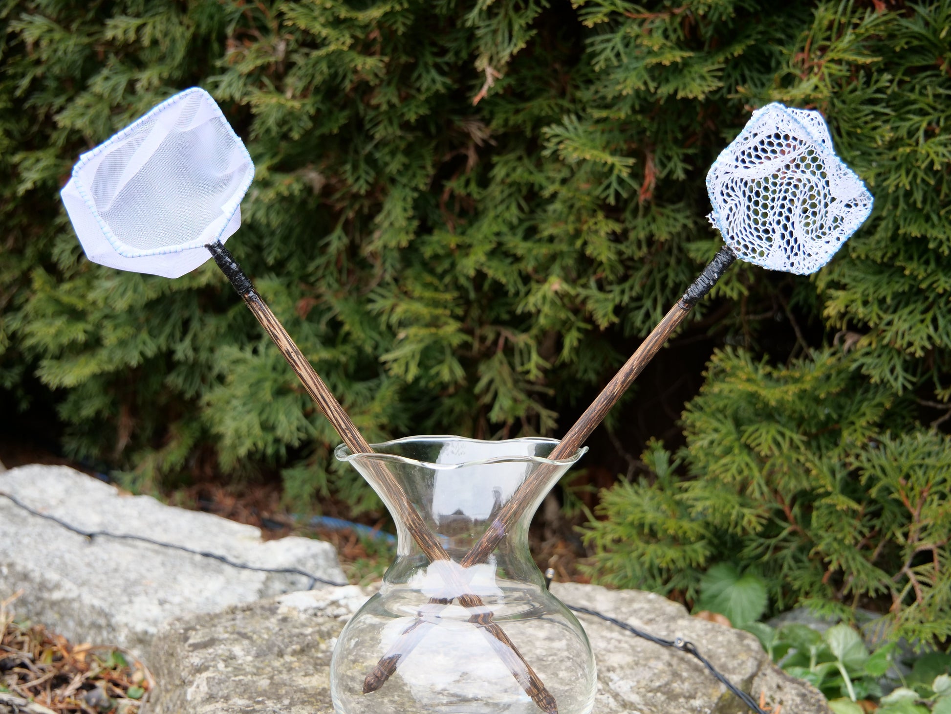 Dekorativer Kescher mit grobem Netz und Holzgriff, ideal für Miniteiche und Aquaristik, auf Stein im Außenbereich