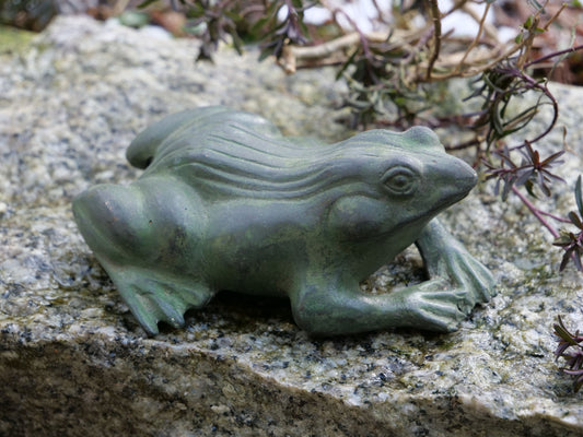 Messingfrosch auf Stein – Naturgetreue Froschfigur aus Messing mit grüner Patina, sitzend auf einer Steinfläche im Garten.