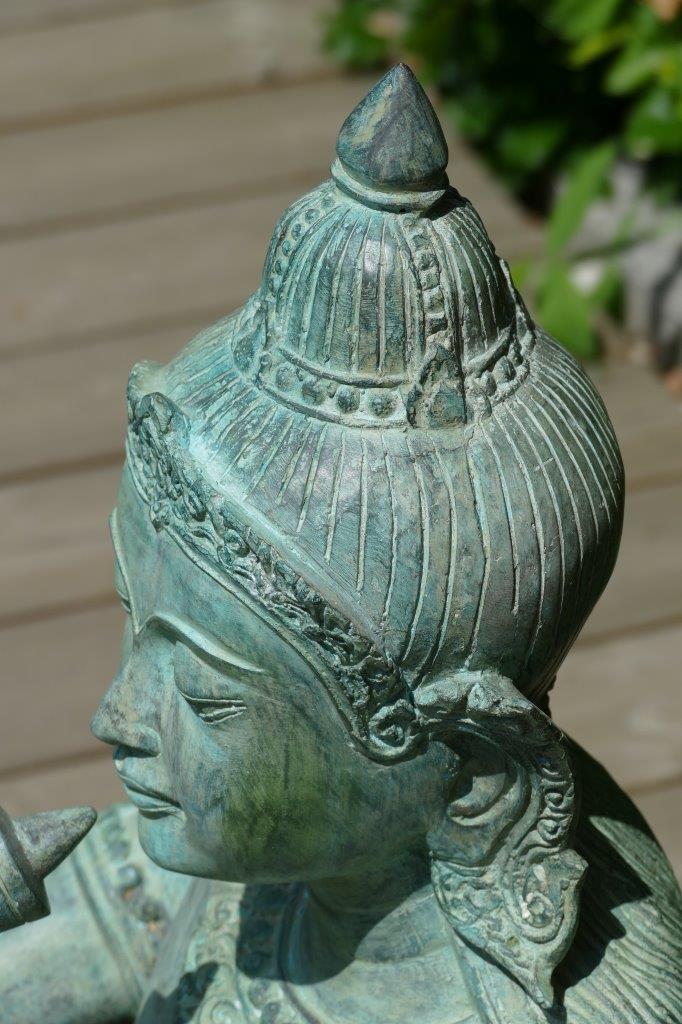 Detailaufnahme der kunstvollen Flötenspieler-Statue aus Messing, filigrane Gesichtszüge und traditionelle Kopfbedeckung