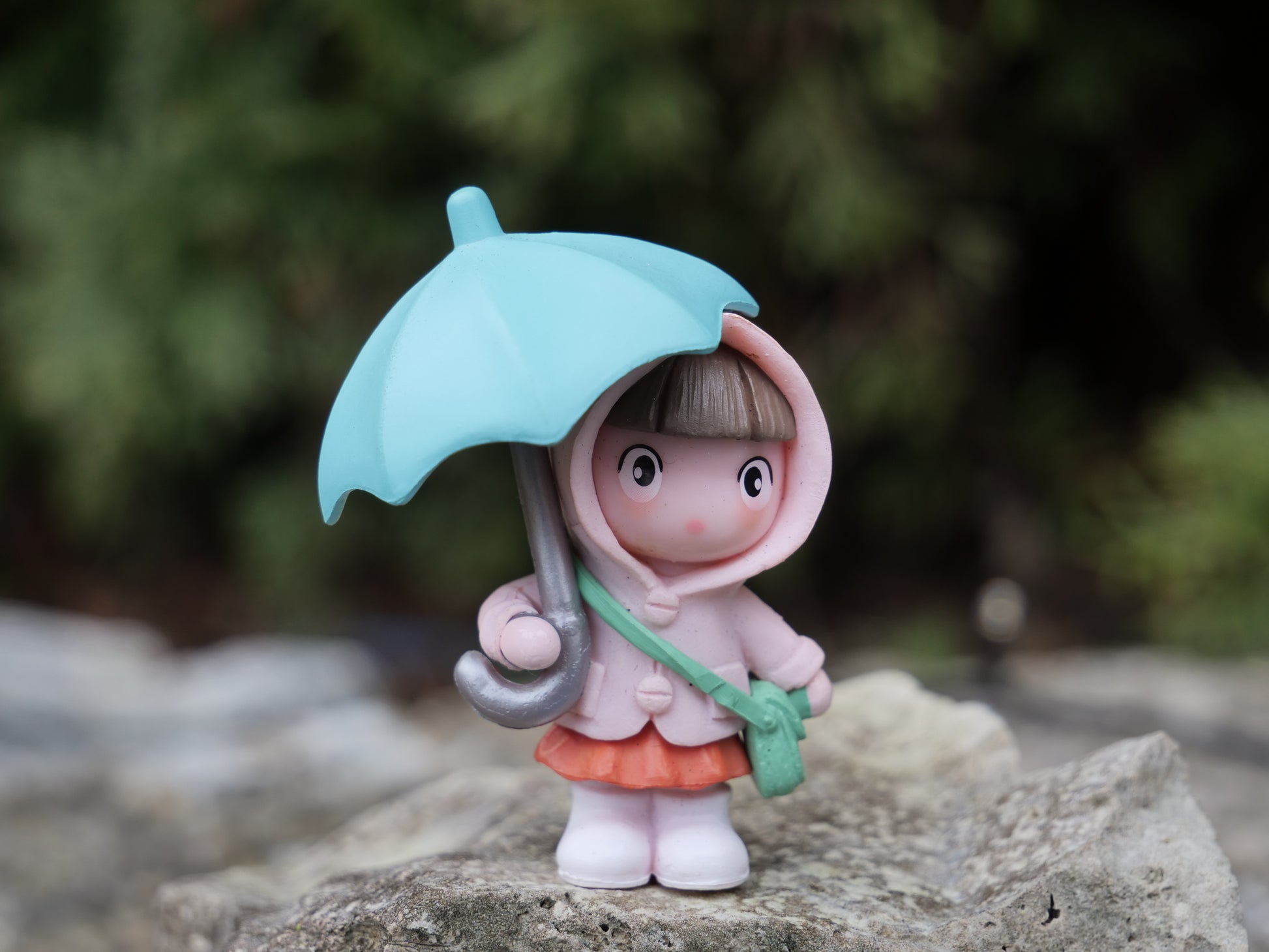 Niedliche Teichfigur: Mädchen mit rosa Mantel, orangefarbenem Rock und türkisem Regenschirm, stehend auf einem Stein. Perfekte Dekoration für Miniteiche und kleine Gartenlandschaften.