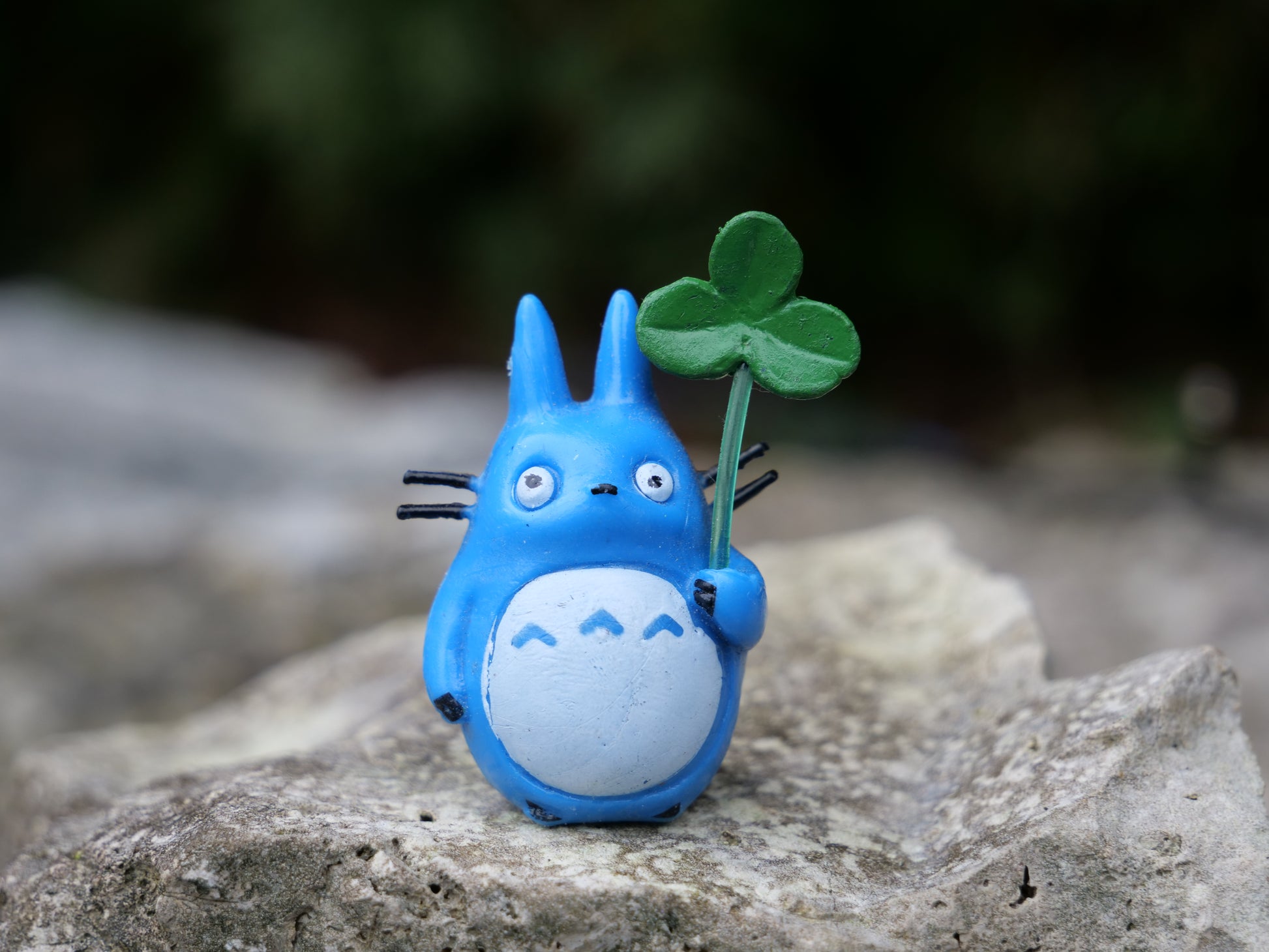 Blaues Knuddelmonster im Anime-Stil, hält ein grünes Kleeblatt in der Hand. Süße Dekoration für Miniteiche, Steingärten und Outdoor-Oasen.