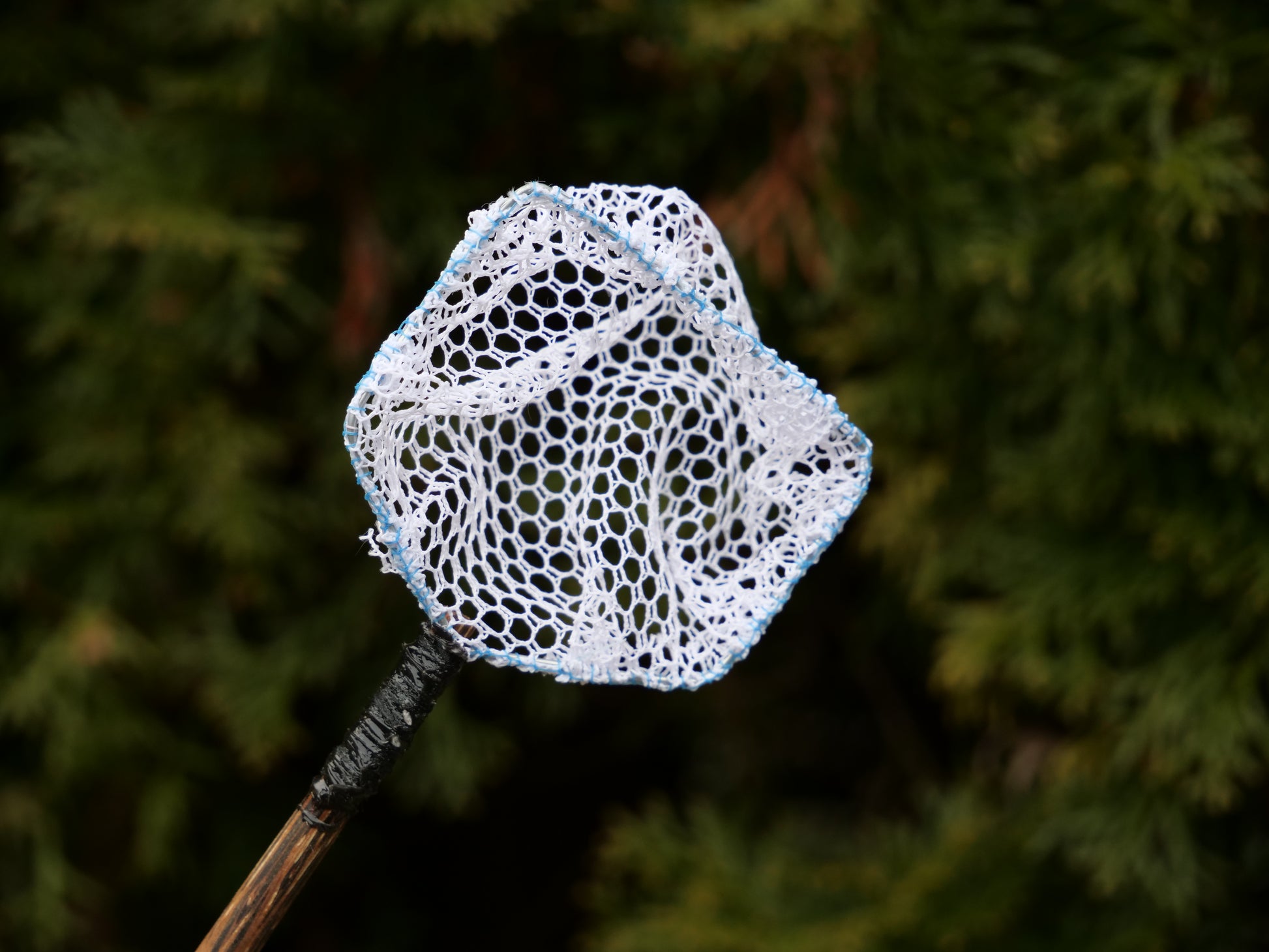 Detailansicht eines Keschers mit grobem Netz und Holzgriff, perfekt zum Entfernen von Schmutzpartikeln aus Miniteichen und kleinen Wasserstellen