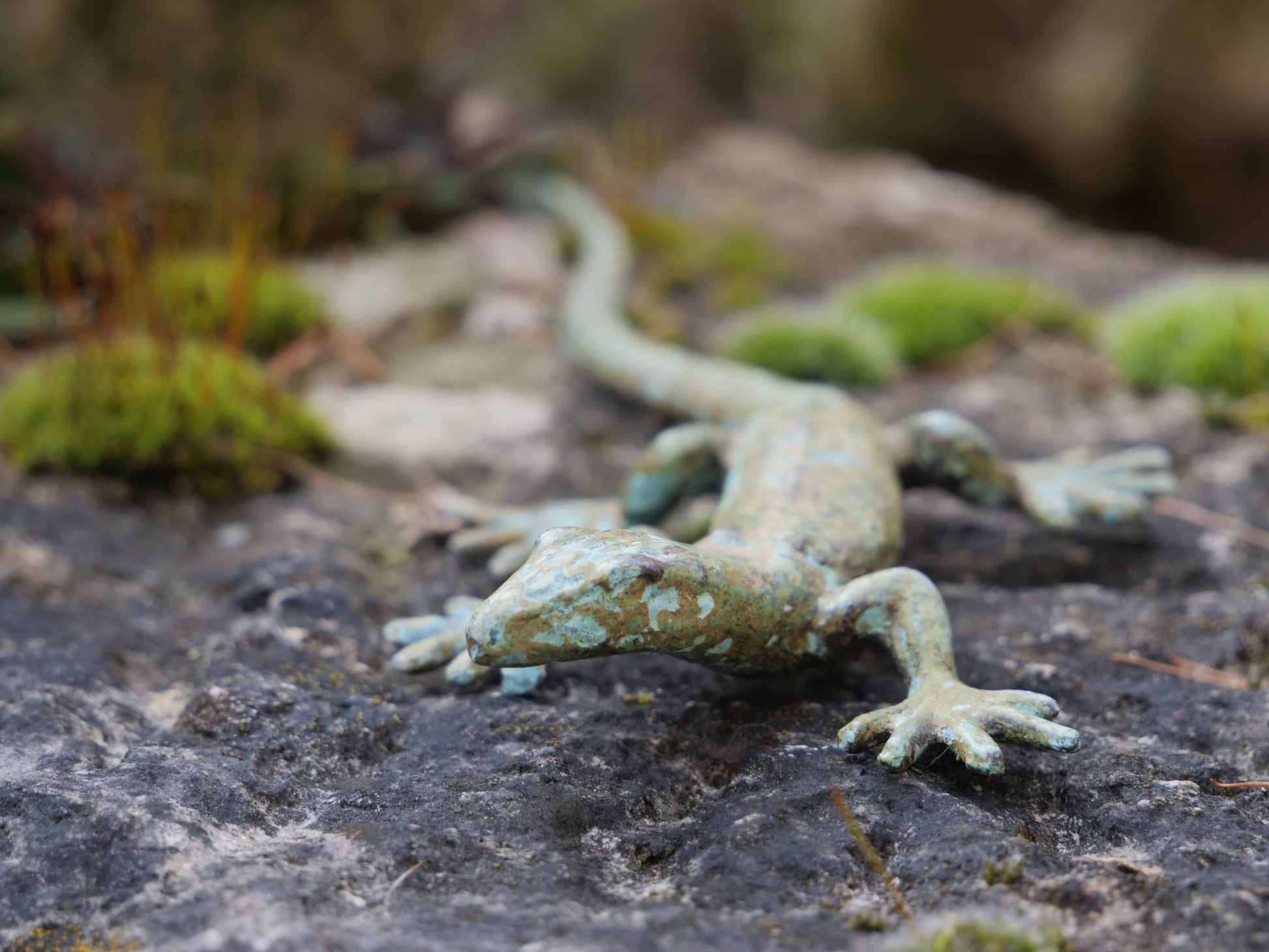 Nahaufnahme eines Messing-Geckos auf Stein, fein detaillierte Patina-Oberfläche für realistische Optik